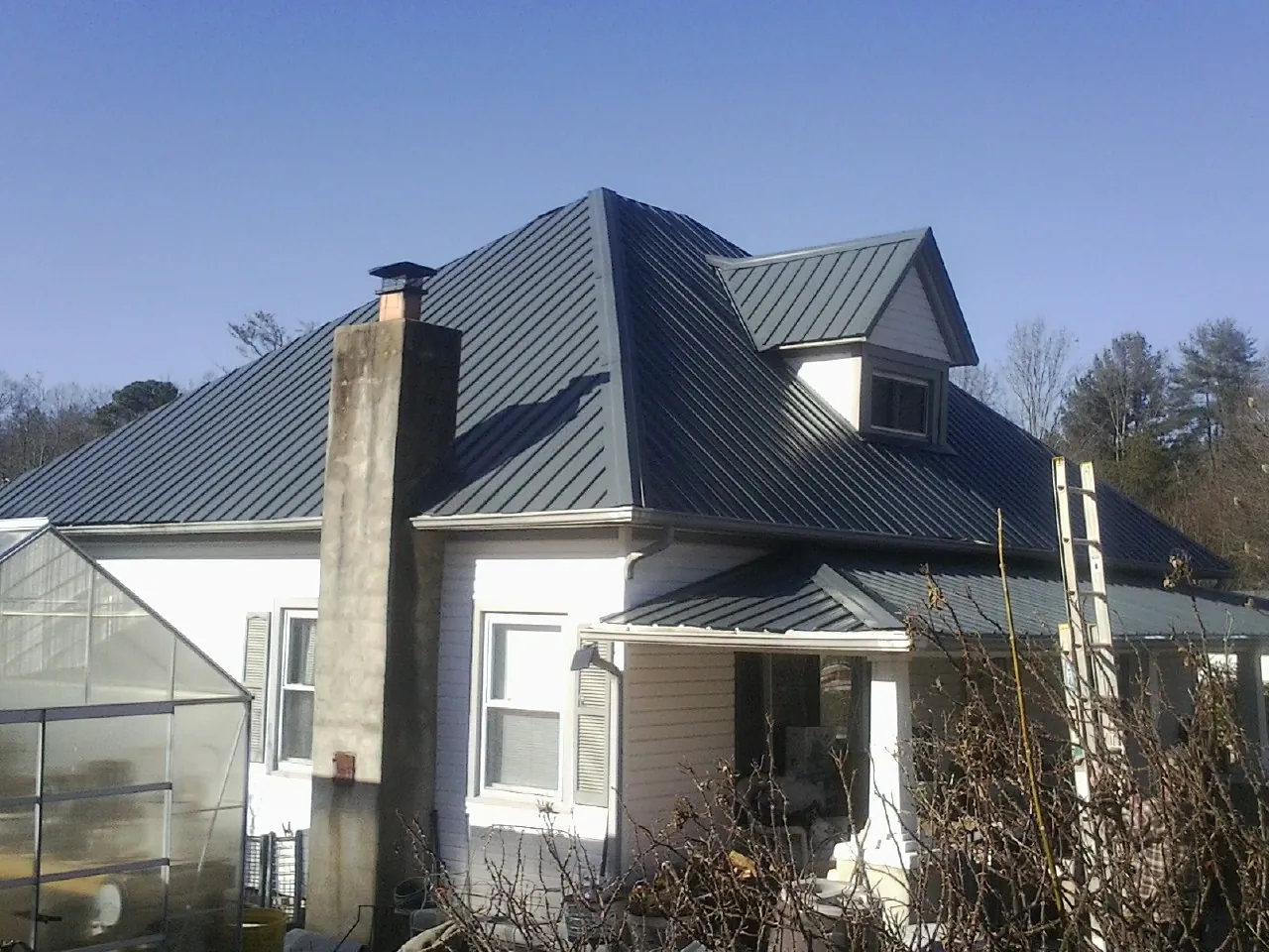 Dark blue standing seam metal roof on a white farmhouse with dormer — Slate & Tile Roof Repair by Roofing Brothers in Beersheba Springs