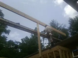 Carpenter setting a ridge beam over a new addition frame — Ice Dam Removal by Roofing Brothers in Beersheba Springs