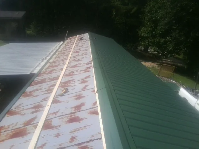 Old rusted panels beside newly installed green metal roofing — Wind Damage Roof Repair by Roofing Brothers in Beersheba Springs