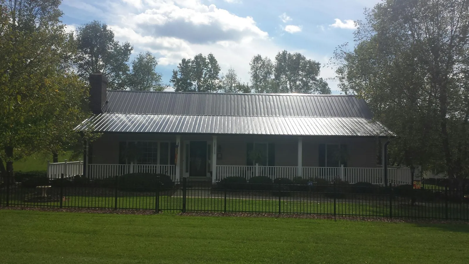 Gray metal roof on a brick ranch with a full width front porch — Gutter Guard Installation work by our crew in Beersheba Springs