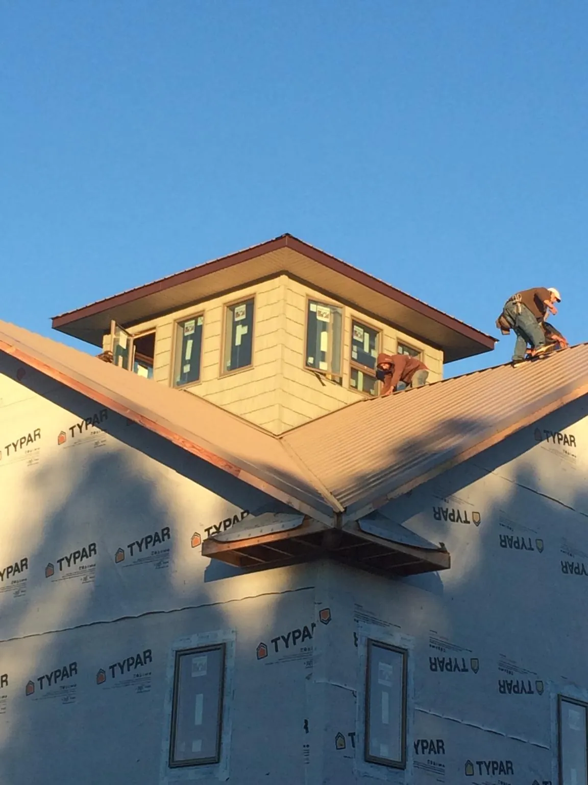 Roofers working around a rooftop cupola on a new metal roof at sunset — Roof Waterproofing in Beersheba Springs by Roofing Brothers